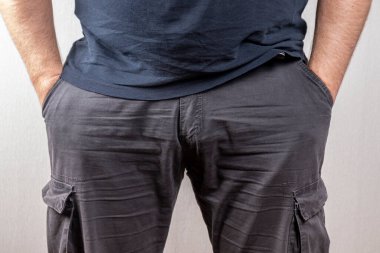 Cesur bir adam ellerini pantolonunun cebinde hafif bir arka planda tutar..