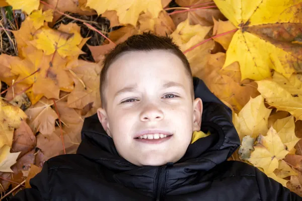 Portrét Usměvavého Desetiletého Chlapce Ležícího Pozadí Žlutých Javorových Listů Koncept — Stock fotografie