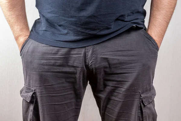 Cesur bir adam ellerini pantolonunun cebinde hafif bir arka planda tutar..