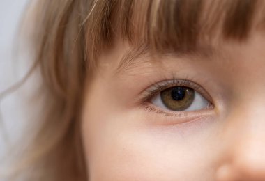 Sarışın, küçük bir kızın yüzünü yakından çek. Çocuğun gözü ve yanağı..