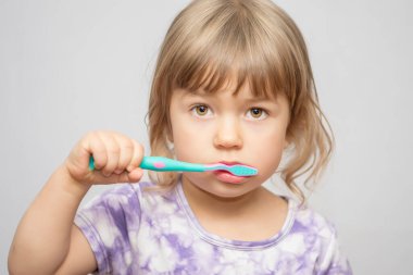 Küçük bir kız dişlerini fırçalıyor. Diş fırçası olan bir kız. Ağız temizliği..