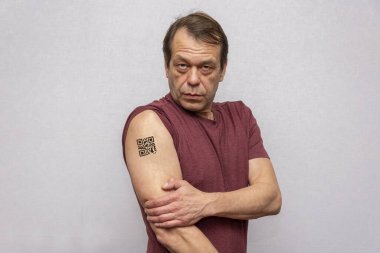 Elinde QR kodu olan yaşlı bir adam, kovid 19 koronavirüse karşı aşı olduğu doğrulandı. Geçici bir dövme. Gezici uygulamayı kullanarak QR kodunu tara. Kanıt bazlı aşılama.