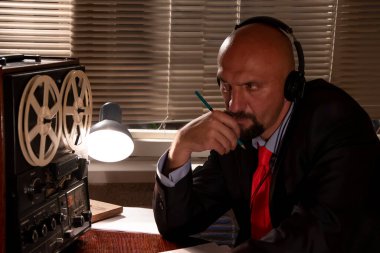 FBI 'dan ya da KGB' den gizli bir ajan kulaklıkları dinler ve konuşmayı bir makaradan makaraya kaydeder, kağıda kalemle ihbar yazar. Vatandaşların gizli telefon kayıtları..