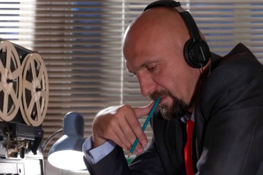 FBI 'dan ya da KGB' den gizli bir ajan kulaklıkları dinler ve konuşmayı bir makaradan makaraya kaydeder, kağıda kalemle ihbar yazar. Vatandaşların gizli telefon kayıtları..