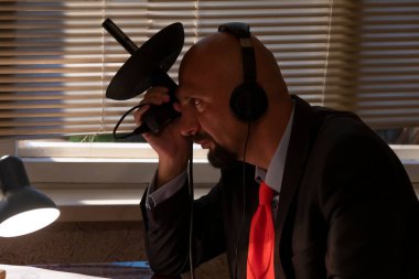 FBI 'dan ya da KGB' den gizli bir ajan kulaklıkları dinliyor ve elinde yönlendirmeli bir mikrofon tutarak konuşmayı makaradan makaraya kaydediyor. Vatandaşların gizli telefon kayıtları..