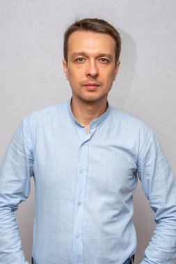 30-35 yaşlarında, açık tişörtlü, izole edilmiş gri arka planda kameraya bakan duygusal bir adamın portresi..