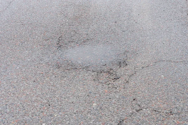 雨后沥青路面上的一个洞 春天过后道路上的一个坑洞融化了 — 图库照片