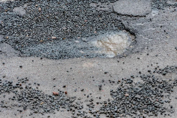 雨后沥青路面上的一个洞 春天过后道路上的一个坑洞融化了 — 图库照片