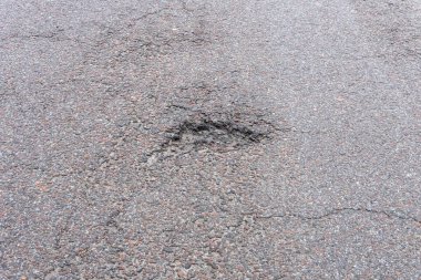 Asfalt yolda küçük çukurlar, çukurlar ve tahrip edilmiş yol yüzeyinde.