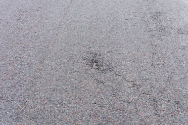 Asfalt yolda küçük çukurlar, çukurlar ve tahrip edilmiş yol yüzeyinde.
