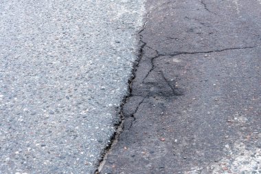 Asfalt yolda küçük çukurlar, çukurlar ve tahrip edilmiş yol yüzeyinde.