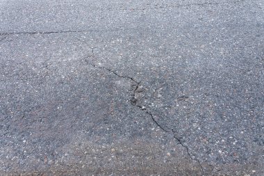 Asfalt yolda küçük çukurlar, çukurlar ve tahrip edilmiş yol yüzeyinde.