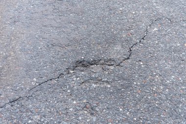 Asfalt yolda küçük çukurlar, çukurlar ve tahrip edilmiş yol yüzeyinde.