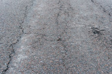 Asfalt yolda küçük çukurlar, çukurlar ve tahrip edilmiş yol yüzeyinde.