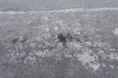 Asfalt yolda küçük çukurlar, çukurlar ve tahrip edilmiş yol yüzeyinde.