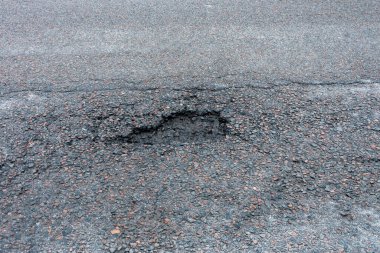 Asfalt yolda küçük çukurlar, çukurlar ve tahrip edilmiş yol yüzeyinde.