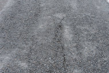 Asfalt yolda küçük çukurlar, çukurlar ve tahrip edilmiş yol yüzeyinde.