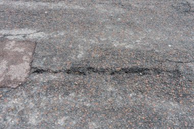 Asfalt yolda küçük çukurlar, çukurlar ve tahrip edilmiş yol yüzeyinde.