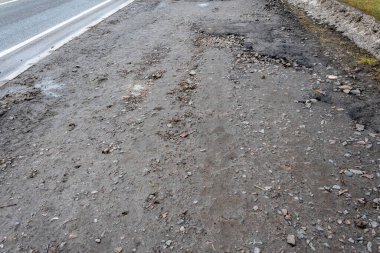 Asfalt yolda küçük çukurlar, çukurlar ve tahrip edilmiş yol yüzeyinde.