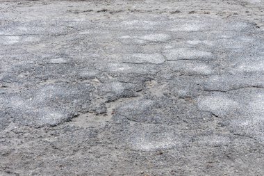 Asfalt yolda küçük çukurlar, çukurlar ve tahrip edilmiş yol yüzeyinde.