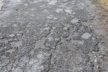Asfalt yolda küçük çukurlar, çukurlar ve tahrip edilmiş yol yüzeyinde.