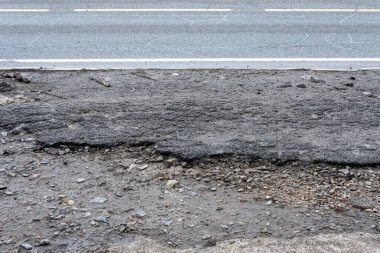 Asfalt yolda küçük çukurlar, çukurlar ve tahrip edilmiş yol yüzeyinde.
