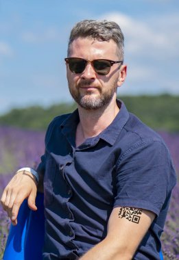 Elinde QR kodu olan gözlüklü bir adamın portresi, kovid 19 koronavirüse karşı aşı olduğu doğrulandı. Geçici bir dövme. Gezici uygulamayı kullanarak QR kodunu tara. Kanıt bazlı aşılama.