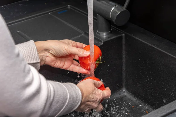 Elderly Woman Washes Red Tomatoes Running Water Tap Kitchen Close — стоковое фото