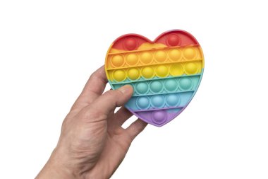 Bir adamın eli stres önleyici bir oyuncağı oynuyor. Beyaz bir arka planda, izole edilmiş bir gökkuşağı kalbi. Yeni renkli kabarcıklar.
