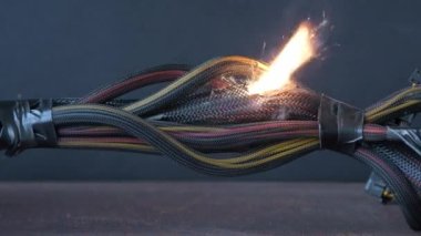 Kablolar yanıyor ve arka planda kıvılcım saçıyor. Bilgisayarın kablolarındaki kısa devre. Alevler, kıvılcım ve duman.