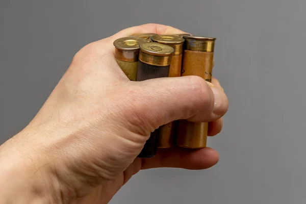 Hunting cartridges are clamped in a man's hand.  Concept: male hobby, bird hunting, large caliber.