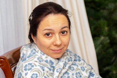 40 yaşında güzel bir kadının portresi. Kışın bir dairede ekoseye sarılmış..