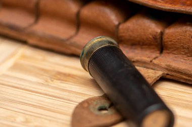 Deri bir bandocunun arka planındaki av fişeği desenli arka planda, yakın plan, seçici odaklanma. Konsept: kuş avı, büyük ve küçük kalibreli avlanma mühimmatı.