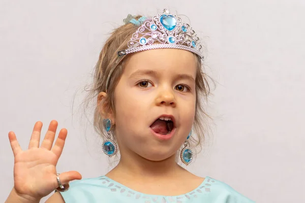 一个戴着王冠和耳环的小女孩把玩具戒指 儿童珠宝和服装珠宝展示在她的手上 — 图库照片