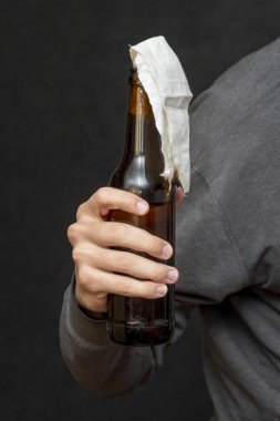 Bir adam elinde koyu bir arka planda molotof kokteyli tutuyor, onu ateşe vermeye hazırlanıyor, yakın plan, seçici odaklanma..