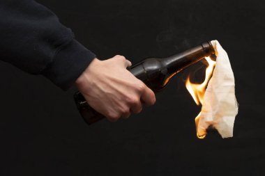 Molotof kokteyli koyu arka planda, yakın planda, seçici odaklı bir çakmakla tutuşturulur. Kavram: sokak isyanları, devrimci hareket, savunma ve savunma, Ukrayna 'da savaş.