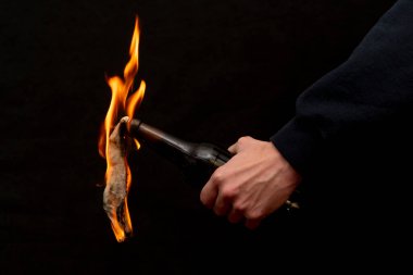 Molotof kokteyli koyu arka planda, yakın planda, seçici odaklı bir çakmakla tutuşturulur. Kavram: sokak isyanları, devrimci hareket, savunma ve savunma, Ukrayna 'da savaş.