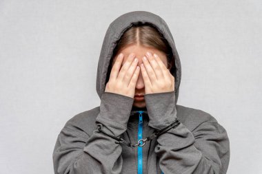 Genç bir kız kelepçelenmiş, yüzünü kapüşonlu, gri bir arka planda gizliyor. Çocuk suçlular, reşit olmayanların cezai yükümlülükleri. Gençlik suç örgütü üyeleri ve çeteler.