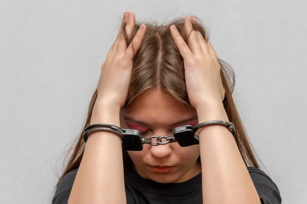 灰色の背景に クローズアップ手錠をかけられた若い女の子 黒のTシャツの少年非行 未成年者の刑事責任 — ストック写真