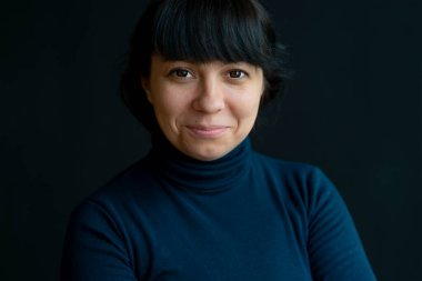40 yaşındaki yetişkin bir kadının, koyu arka planda siyah bir süveter giyen, yakın plan seçici odaklı gözleri için CONTACT lensli portresi. Bir esmerin duygusal portresi.