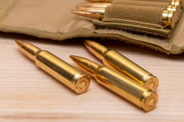 Tahta arka planda 7.62 kalibrelik bir askeri bandocuda kurşun bulunan sarı muharebe tüfeği fişekleri..