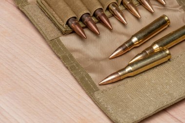 Tahta bir arka planda 7.62 kalibrelik fişekleri ve kurşunları olan askeri bir sancak..