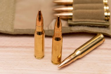 Tahta arka planda 7.62 kalibrelik bir askeri bandocuda kurşun bulunan sarı muharebe tüfeği fişekleri..