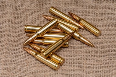 Kalaşnikof taarruz tüfeği için 7.62 kalibrelik mermilerin etrafa saçılması, yakın plan, seçici odaklanma. Konsept: ödünç verilmiş silah satışı, mühimmat yardımı, silah tedariği.
