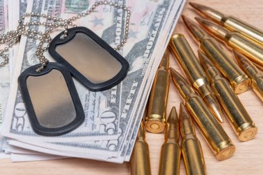 Amerikan dolarlarının arka planına karşı, gerçek cephane ve ordu kimlik madalyonları. Konsept: Askeri özel operasyon, silah tedariği, savaşın finansmanı.