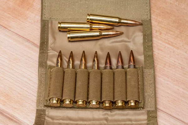 Tahta bir arka planda 7.62 kalibrelik fişekleri ve kurşunları olan askeri bir sancak..