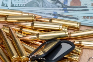 Amerikan dolarlarının arka planına karşı, gerçek cephane ve ordu kimlik madalyonları. Konsept: Askeri özel operasyon, silah tedariği, savaşın finansmanı.