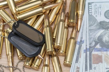 Amerikan dolarlarının arka planına karşı, gerçek cephane ve ordu kimlik madalyonları. Konsept: Askeri özel operasyon, silah tedariği, savaşın finansmanı.