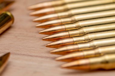 A row of cartridges with 7.62 caliber bullets for a Kalashnikov assault rifle on a textured background, close-up, selective focusing. Concept: sale of weapons under lend-lease, assistance with weapons and ammunition, arms supplies.