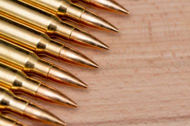 A row of cartridges with 7.62 caliber bullets for a Kalashnikov assault rifle on a textured background, close-up, selective focusing. Concept: sale of weapons under lend-lease, assistance with weapons and ammunition, arms supplies.